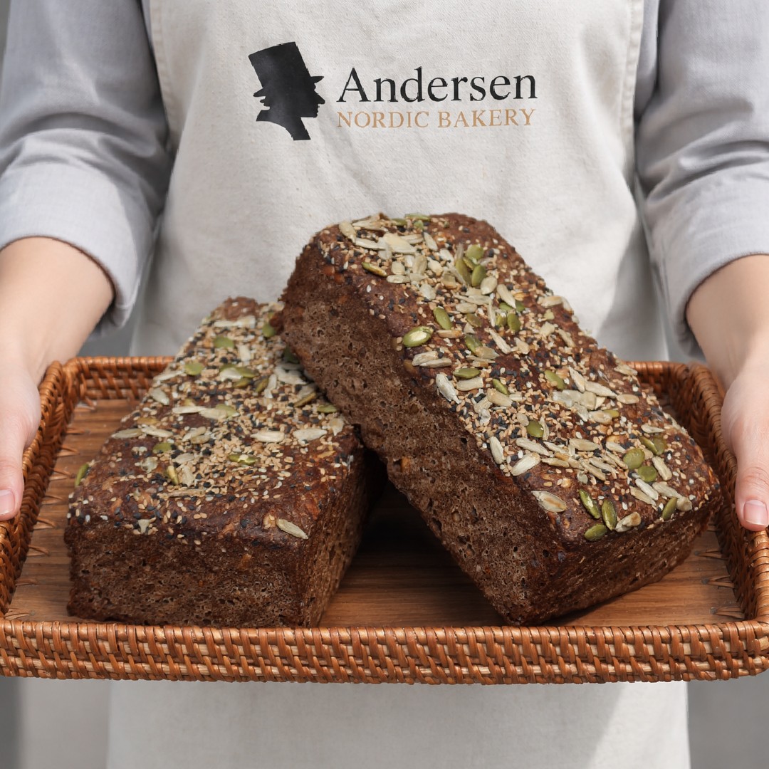 Andersen baker holding a tray of seeded bread