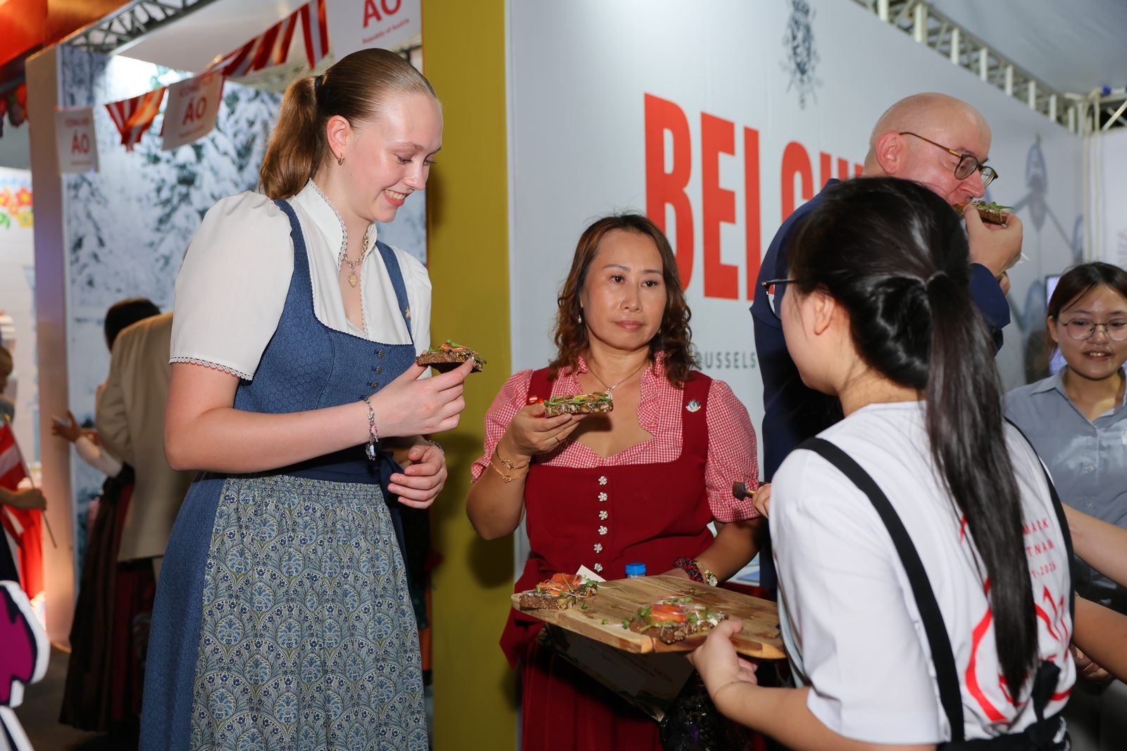 Visitors taste open sandwiches offered on a wooden board by an Andersen team member
