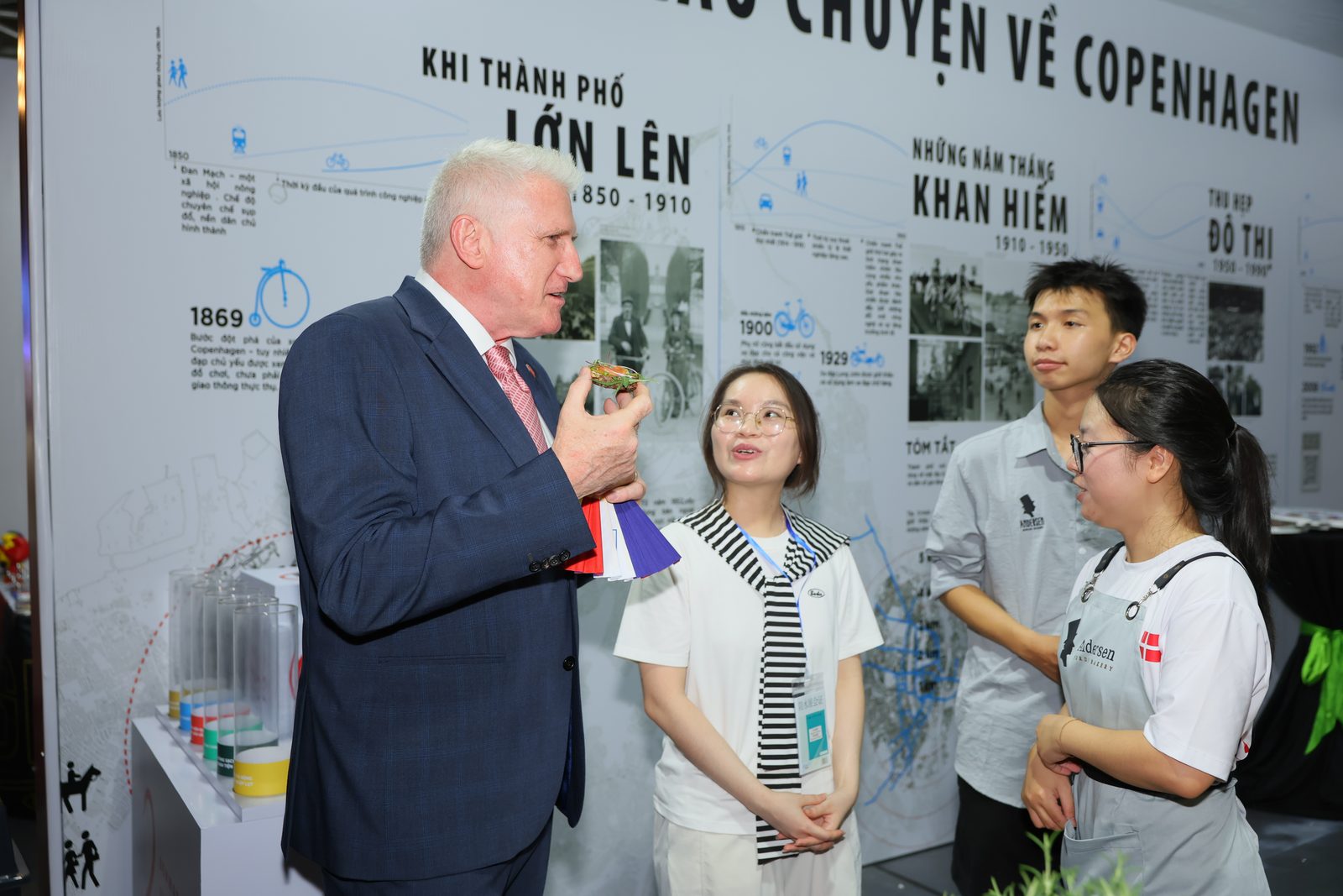 A guest holds an open sandwich while chatting with the Andersen team in front of a Copenhagen exhibit
